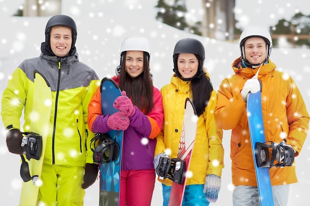 inverno, lazer, esporte radical, amizade e conceito de pessoas - amigos felizes em capacetes com pranchas de snowboard