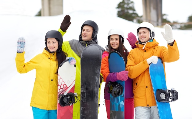 Inverno, lazer, esporte radical, amizade e conceito de pessoas - amigos felizes em capacetes com pranchas de snowboard