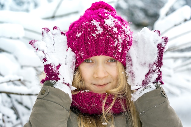 Inverno - menina feliz e sorridente ao ar livre na época da queda de neve