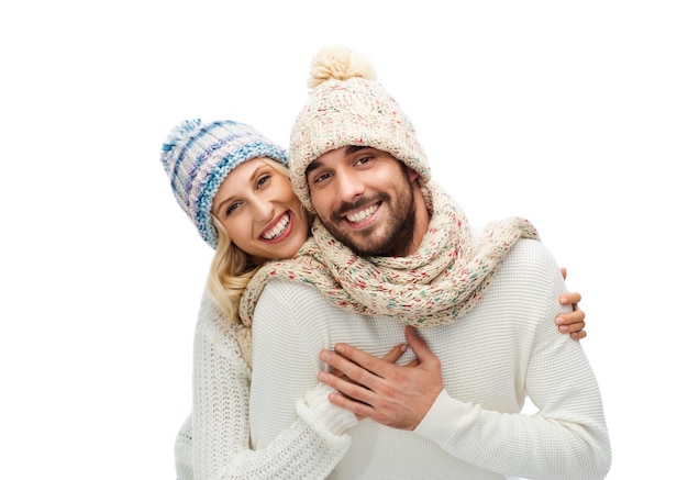 inverno, moda, casal, natal e conceito de pessoas - sorrindo homem e mulher em chapéus e cachecol abraçando