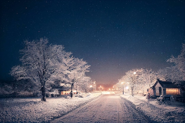 Inverno nevado pequena rua aconchegante com luzes em casas, paisagem noturna da cidade de neve caindo.