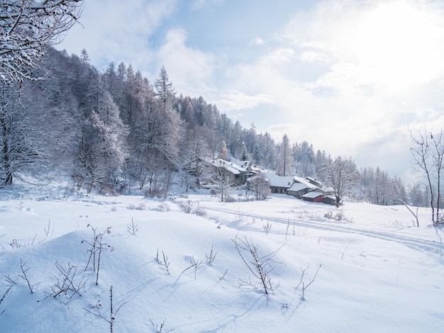 Inverno nos alpes italianos bela vista da aldeia idílica na floresta nevada e picos de montanhas cobertas de neve piemonte itália