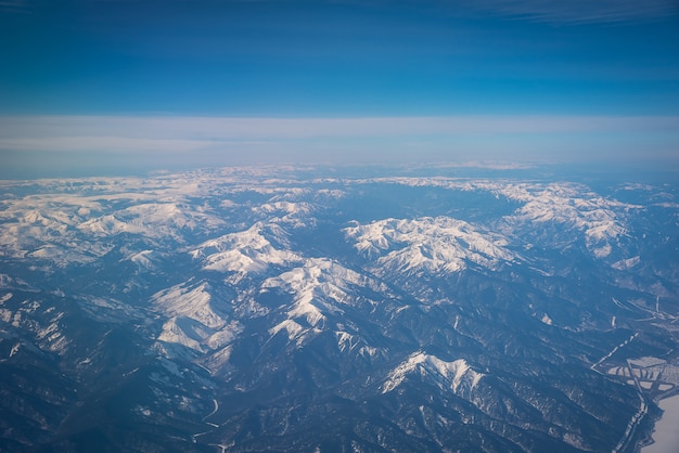 Inverno pico montanhas com neve da janela do avião.