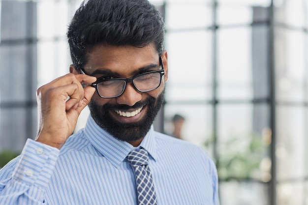 Inversionista masculino barba mirando a la cámara y sonriendo en la oficina moderna