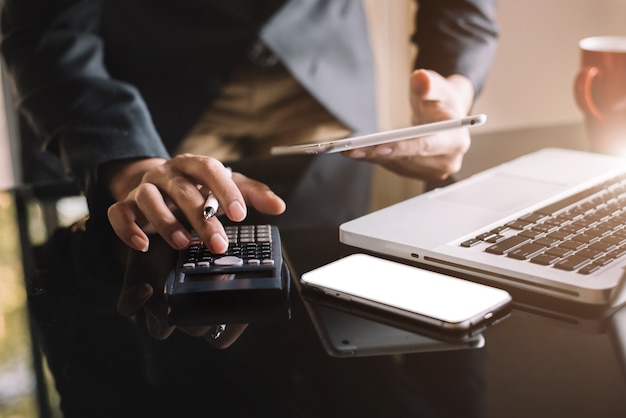 Los inversores están calculando los costos de inversión de la calculadora y tienen una tableta y una computadora en la oficina en casa.