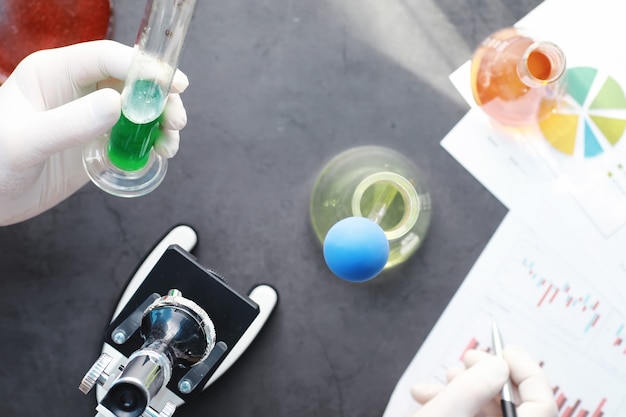 Investigación de laboratorio. Prueba de drogas. Experimentos químicos en el laboratorio. Microscopio varios tubos de ensayo y vasos de precipitados sobre la mesa en el oficial médico.