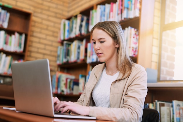 Investigación de mecanografía y mujer en la biblioteca con educación portátil y preparación para exámenes en la universidad Estudiante de tecnología y estudio en la mesa para la comunicación de conocimientos y aprendizaje en internet