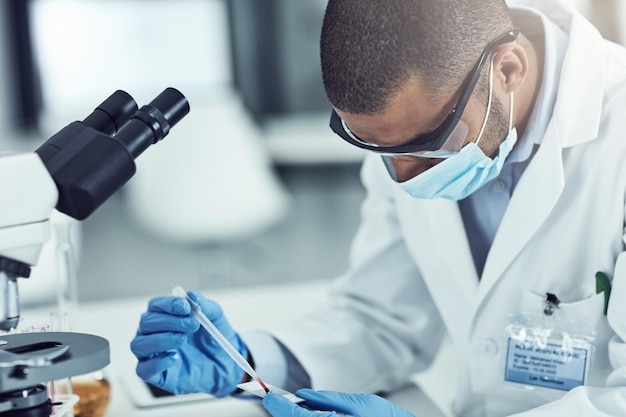 Investigación médica científica y desarrollo de medicamentos con un científico masculino que prueba una muestra de sangre con un microscopio Técnico de laboratorio masculino que trabaja para descubrir nuevas innovaciones y avances en el tratamiento