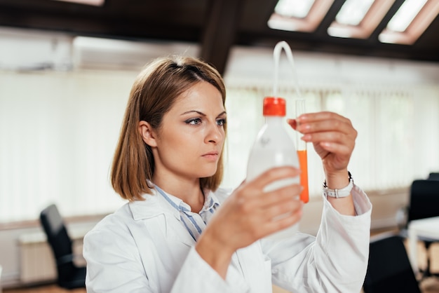 Investigador científico que sostiene un agua en botellas de plástico con una bomba. De cerca.