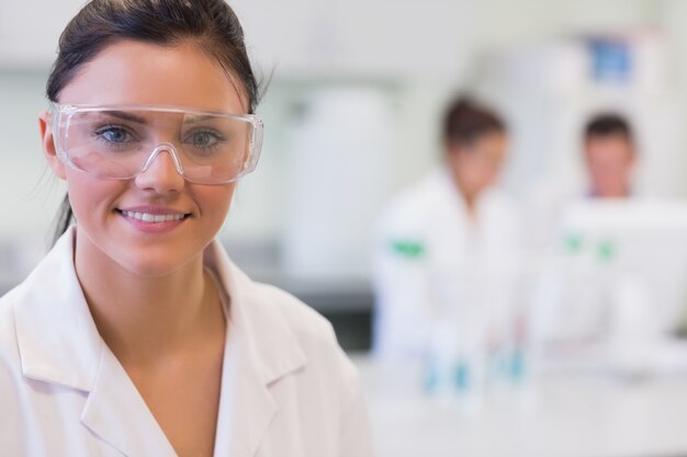 Foto investigador femenino con colegas en segundo plano en el laboratorio