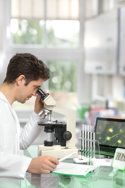 Investigador masculino con microscopio en un centro de investigación moderno