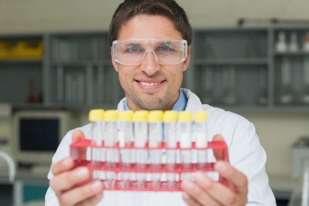 Investigador masculino sorridente com tubos de ensaio no laboratório