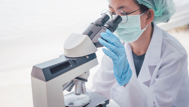 Investigador médico femenino mirando un microscopio en un laboratorio médico. Concepto experimental médico