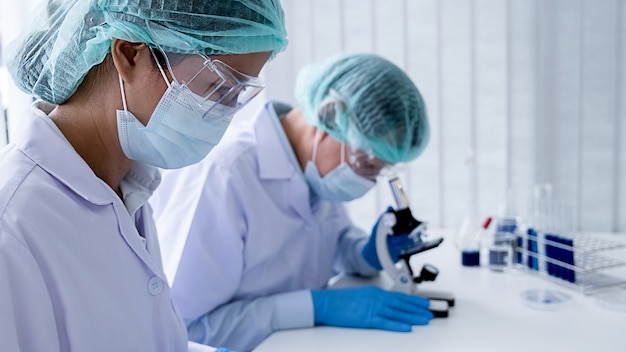 Investigador médico o científico o médico hombre mirando un tubo de ensayo de solución transparente en un laboratorio