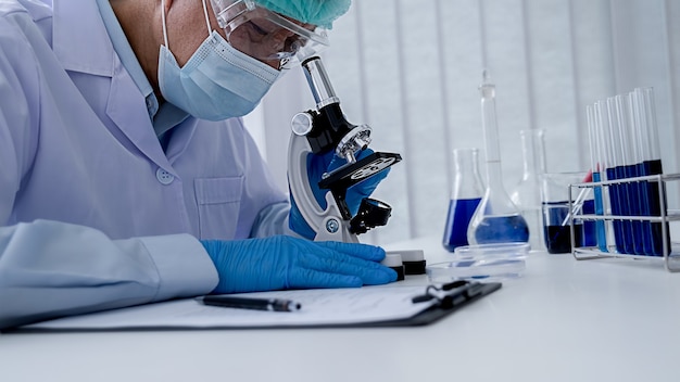 Foto investigador médico o científico o médico hombre mirando un tubo de ensayo de solución transparente en un laboratorio