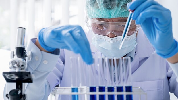 Foto investigador médico o científico o médico hombre mirando un tubo de ensayo de solución transparente en un laboratorio