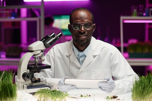 Un investigador de plantas sentado en su escritorio en el laboratorio mirando a la cámara