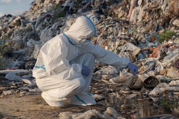 Un investigador con ropa de protección está agachado en un vertedero analizando residuos y contaminantes