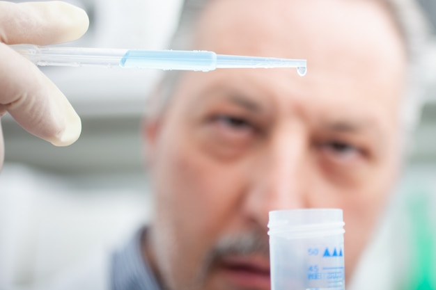 Investigador sosteniendo frasco con líquido azul en el laboratorio, concepto de investigación de coronavirus