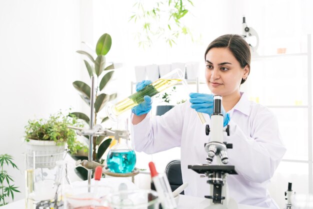 Investigadora científica de Oriente Medio enjuague el líquido de un cilindro graduado a un tubo de ensayo para el análisis de líquidos en el laboratorio Científico que trabaja con un tubo de ensayo y un cilindro graduado