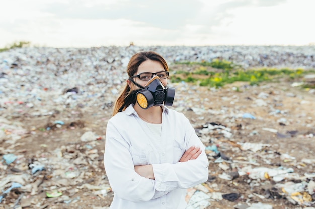 Foto investigadora en una mascarilla protectora en un vertedero evalúa el nivel de contaminación ambiental