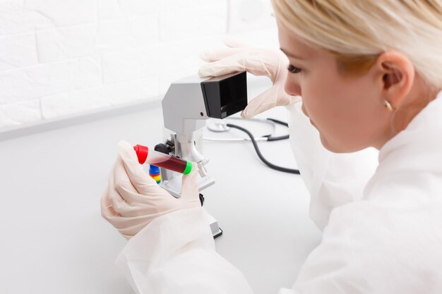 Una investigadora médica o científica hermosa que usa su microscopio en un laboratorio.