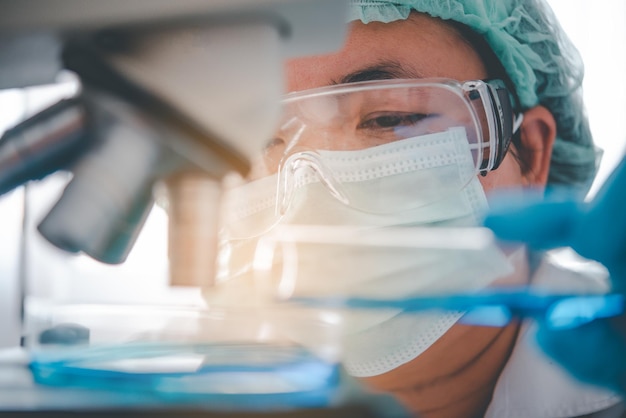 Investigadora médica de primer plano mirando un tubo de vidrio con un líquido que está haciendo experimentos microscópicos. En un laboratorio médico. Concepto médico experimental