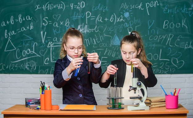 Investigando. ciencia biología. Niñas felices. Las niñas científicas trabajan con microscopio. Investigación química. experimentos científicos en laboratorio. Niñas en el laboratorio de la escuela. La ciencia es futuro.