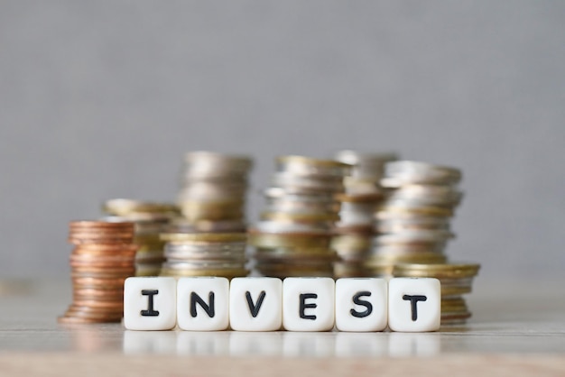 Investir e uma moeda no fundo da mesa de madeira investem o conceito de economia empresarial de dinheiro e investimentos financeiros