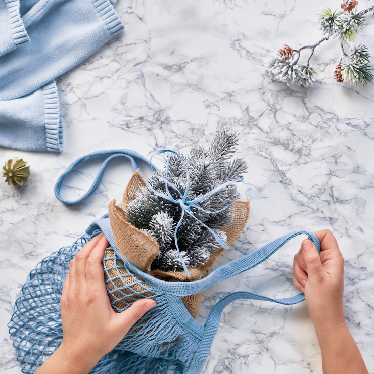 Foto invierno, creativo y plano con árbol de navidad de plástico artificial en una bolsa de cuerda ecológica de color verde menta