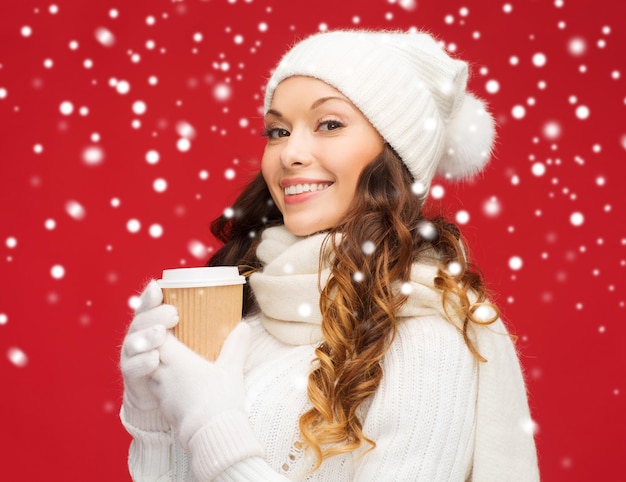 invierno, gente, felicidad, bebida y concepto de comida rápida - mujer con sombrero con taza de café o té para llevar