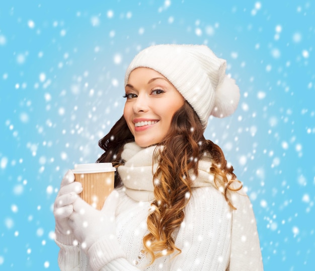 invierno, gente, felicidad, bebida y concepto de comida rápida - mujer con sombrero con taza de café o té para llevar