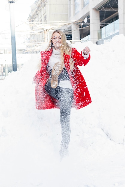 Invierno, moda, concepto de personas - retrato de moda de una bella mujer joven camina por la ciudad sonriendo copos de nieve de primer plano de abrigo de piel rojo frío invierno, respirar aire fresco en el día de invierno helado