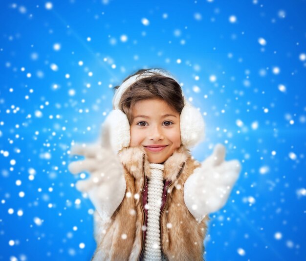 invierno, navidad, infancia, felicidad y concepto de la gente - niña sonriente con ropa de invierno