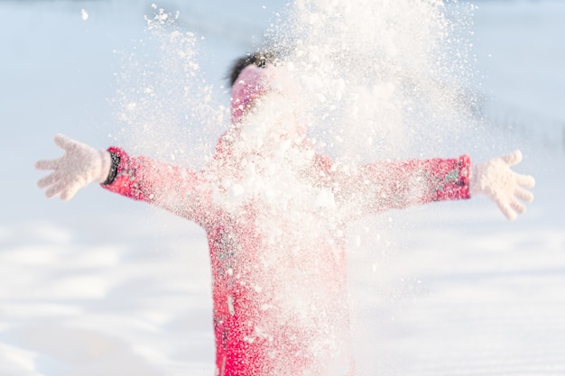 Invierno, una niña juega afuera tirando nieve