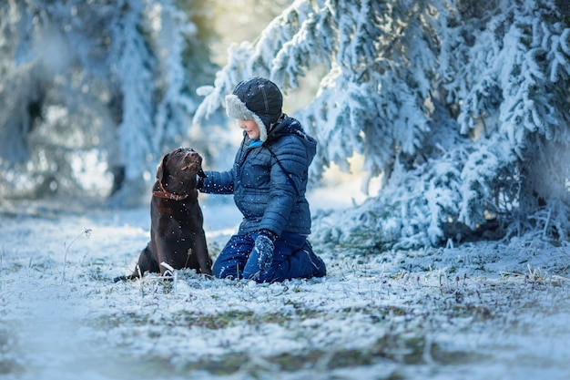 invierno, niño jugando con perro en bosque de invierno