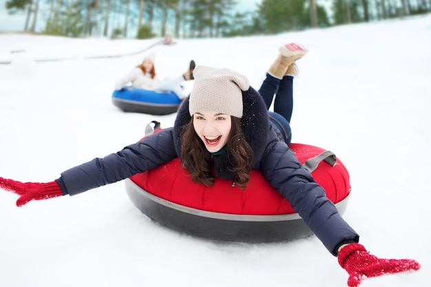 invierno, ocio, deporte, amistad y concepto de personas - grupo de amigos felices deslizándose sobre tubos de nieve