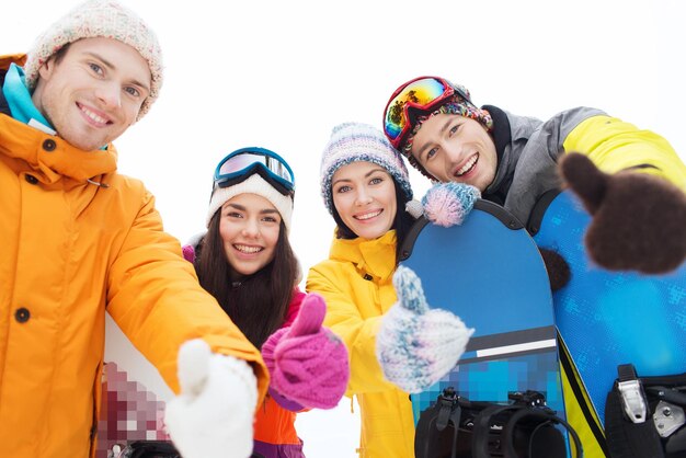 invierno, ocio, deporte extremo, amistad y concepto de personas - amigos felices con tablas de snowboard mostrando los pulgares hacia arriba