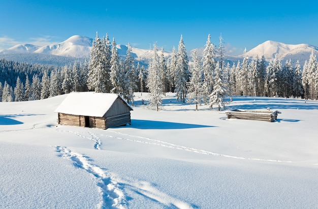 Invierno tranquilo paisaje de montaña con cobertizo y monte Ridge detrás