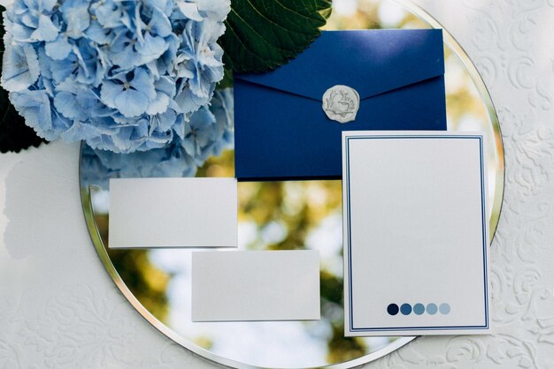 Foto invitación de boda en un sobre gris en una mesa con ramas verdes