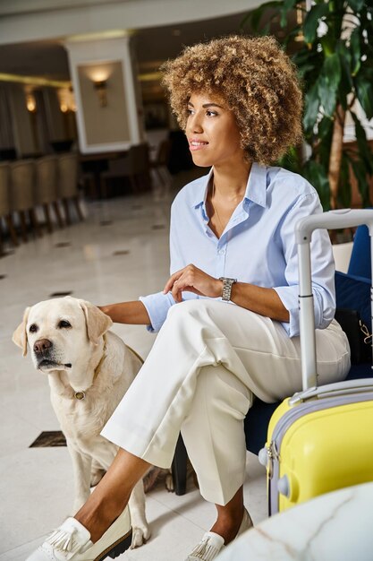 un invitado feliz esperando a registrarse con un perro en un hotel apto para mascotas mujer negra con un reloj de pulsera moderno