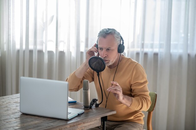 Involucrado. Un hombre de pelo gris con auriculares negros hablando en el micrófono y mirando interesado