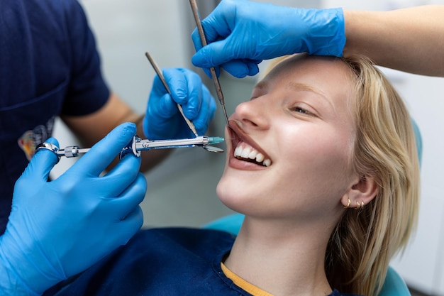 Inyección de anestesia Analgésico Dentista examinando los dientes de un paciente en la oficina de odontología moderna Imagen recortada de primer plano con copyspace Doctor en máscara facial médica desechable