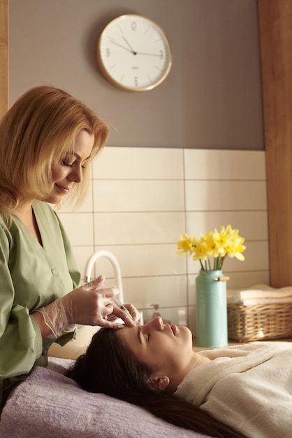 Inyección de belleza Mujer haciendo corrección de la nariz y los labios en el salón