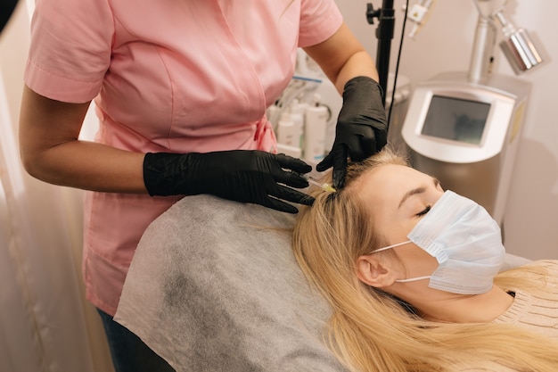 Foto inyección contra la caída del cabello en la cabeza de una mujer rubia en la clínica. mesoterapia. concepto de restauración capilar.