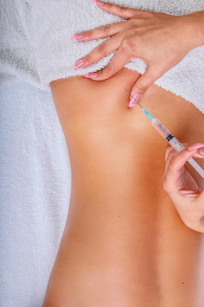 Inyección de jeringa en la espalda de la mujer. Mujer disfrutando de un relajante masaje de espalda en el centro de spa de cosmetología.