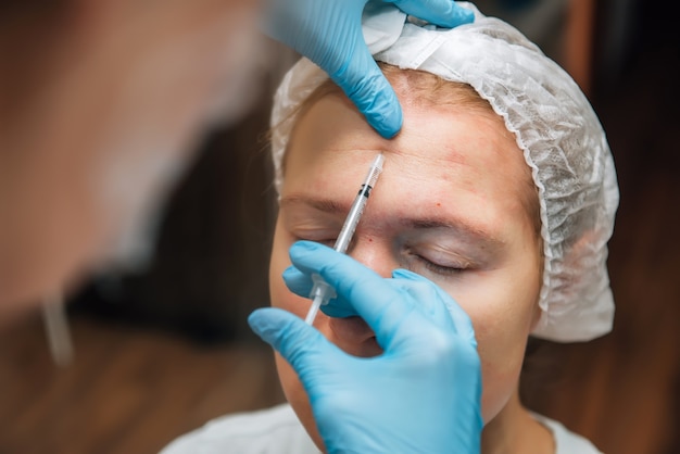 Inyección de relleno de ácido hialurónico debajo de la piel del rostro de la mujer