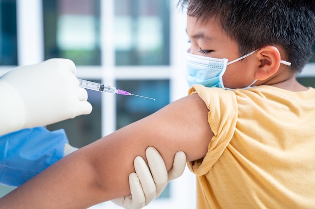 Inyección de vacunación contra la influenza en el brazo, coronavirus, médico que realiza una vacuna en el hombro del paciente niño o niño, vacuna covid-19