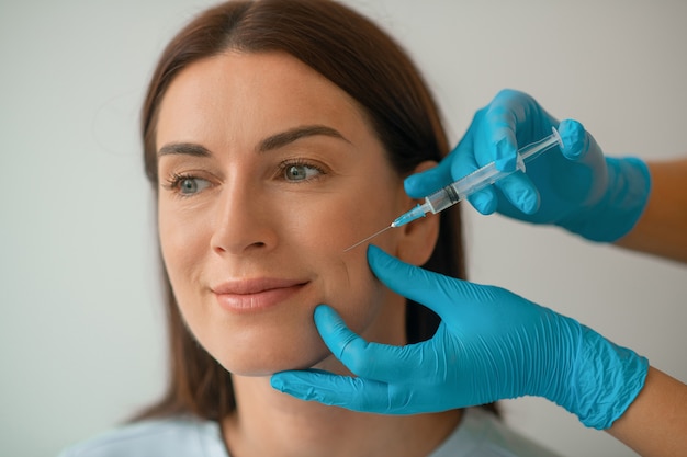 Foto inyecciones de colágeno. cosmetóloga inyectando colágeno en la cara de sus clientes