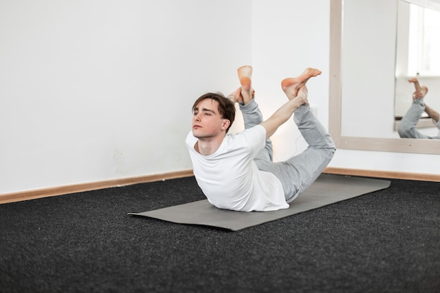 Ioga de jovem em sportswear branco está treinando na sala de fitness. Conceito de meditação e saúde.